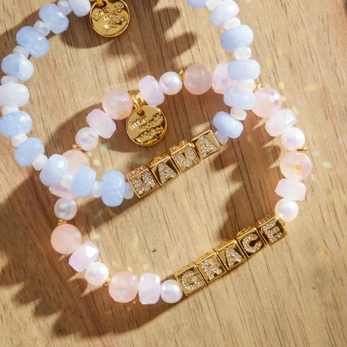 Two beaded bracelets with gold tags and on a wooden surface