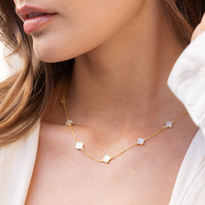 Close-up of a woman wearing a gold necklace and earrings with a blurred background