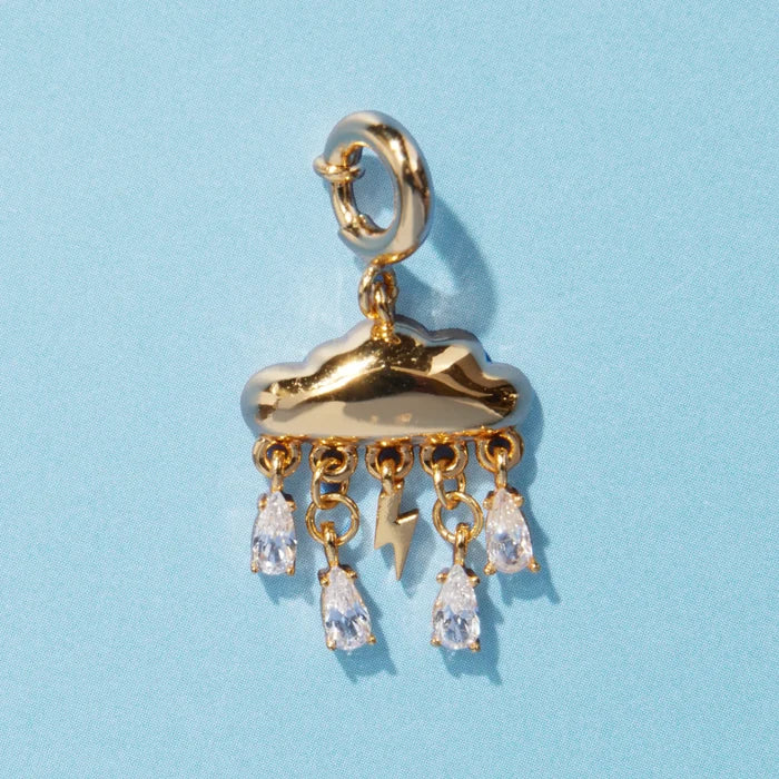 A gold cloud charm with a lightning bolt and five dangling crystal teardrop rhinestones, attached to a spring ring clasp, on a blue background.