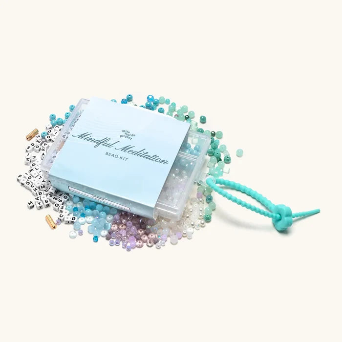 "Mindful Meditation" DIY bead kit with scattered blue, white, and purple beads, letter beads, and a teal stretchy cord.