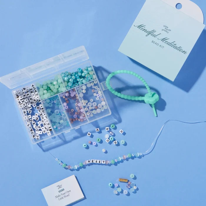 Mindful meditation bead kit against a blue background, open with a few beads scattered around the kit