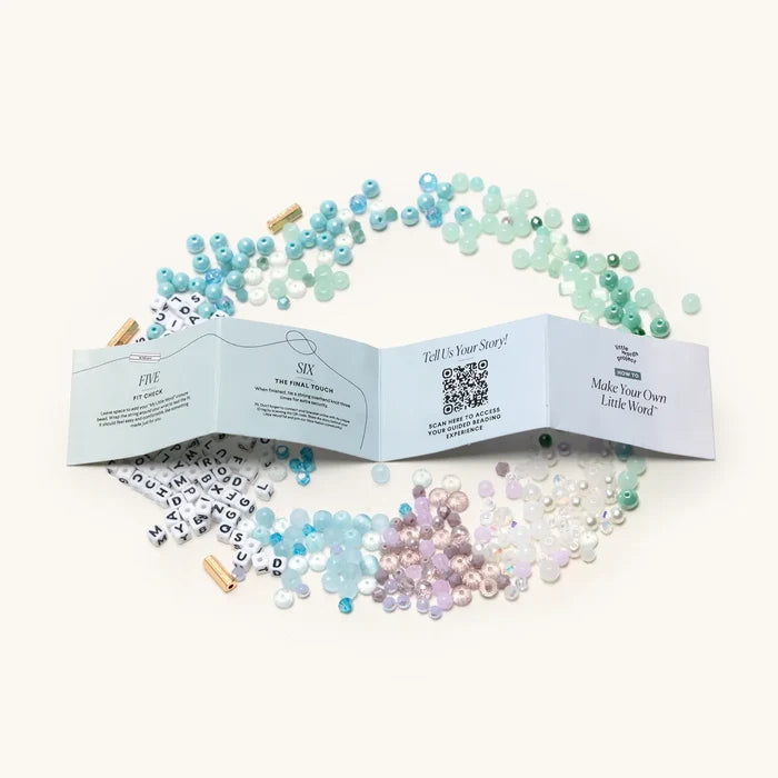 "Mindful Meditation" bead kit with scattered colourful beads, letter beads, teal cord, and an unfolded instruction booklet.