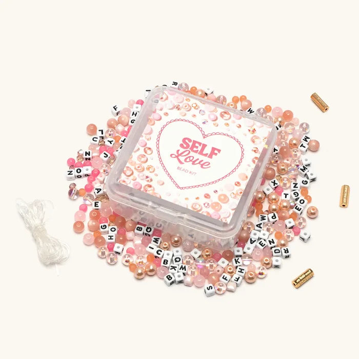 Self Love Bead Kit with pink and blush beads spilled around clear storage box
