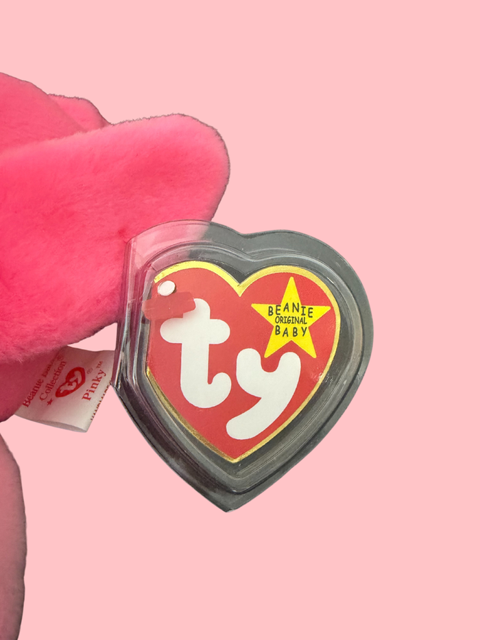 Pink plush toy with a heart-shaped Ty logo tag on a pink background