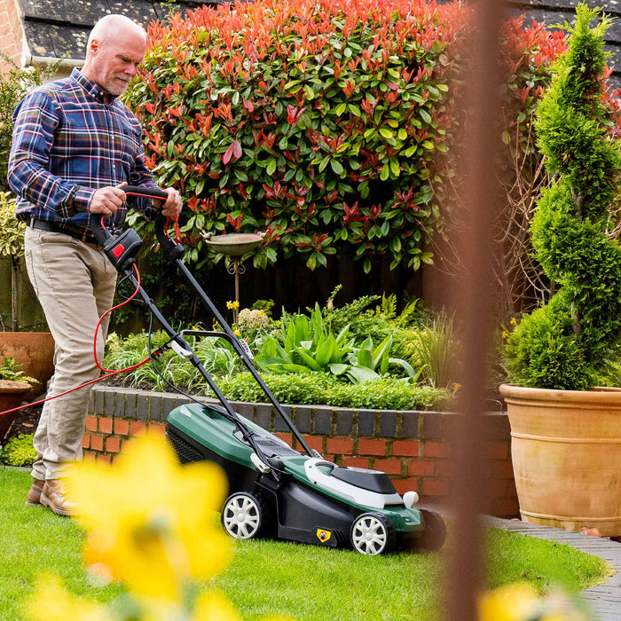 Webb Classic 33cm Elec Rotary Mower with Rear Roller in garden pushed by man